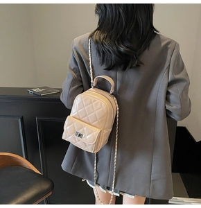 Close-up of beige quilted leather texture and silver chain strap on mini backpack