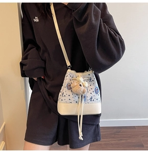 Detail of blue floral bucket bag with drawstring closure and cute plush bear charm