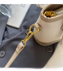 Detail of high-gloss gold hardware and smooth beige leather on the bucket bag