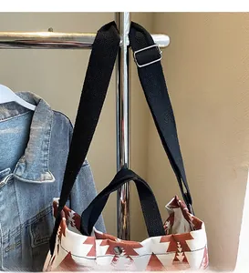 Close-up of canvas tote bag featuring ethnic patterns with adjustable strap and snap closure