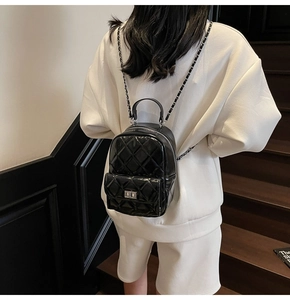 Detail of black quilted mini backpack featuring chain straps and polished metal turn-lock