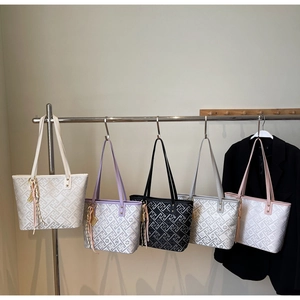 Detail view of five textured tote bags in various colors on a rack for daily commute