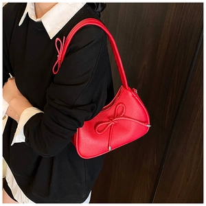 Detail of red bow-knot shoulder bag featuring premium lychee texture and metallic finish