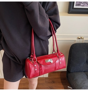 Détail du sac cylindrique en cuir verni rouge avec cadenas en cœur argenté et rivets