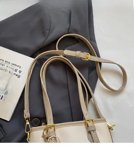 Detail view of adjustable strap with gold buckles on a beige leather bucket bag