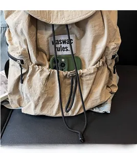 Close-up of khaki nylon backpack front pocket with drawstring and brand logo label