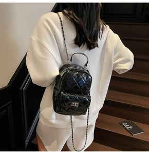 Detail of a black quilted leather mini backpack featuring silver chain and twist lock