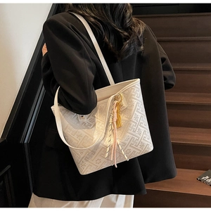 Detailed macro view of white jacquard tote bag with geometric patterns and fringe tassel
