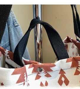 Close-up of durable woven handles and snap button on printed canvas tote bag