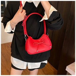 Close-up of red hobo bag featuring bow decorations and grainy textured faux leather