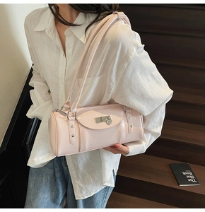 Détail du sac baguette rose brillant avec boucle argentée et rivets sur escalier en bois