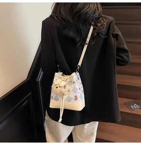 Detail of floral bucket bag with bear print, drawstring closure and plush pendant