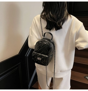 Rear view of a model wearing the black quilted patent leather chain backpack for daily use