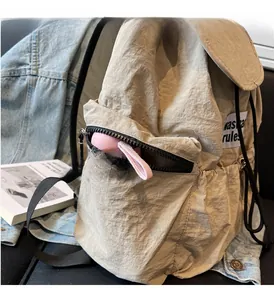 Detail view of beige nylon backpack side zipper pocket with textured fabric finish