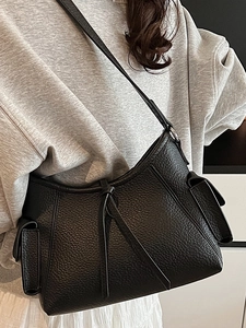 Minimalist black pebble leather shoulder bag with side pockets and decorative straps