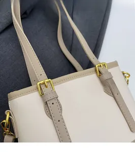 Detailed close-up of beige and brown leather bucket bag showing fine stitching and gold buckle