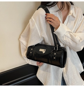 Détail d'un sac bandoulière cylindrique noir avec décor coeur en métal et rivets élégants