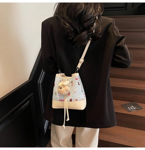 Detail of casual checked bucket bag with brown bear patterns and plush charm on stairs