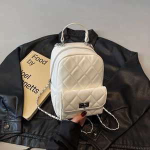 Macro shot of white quilted mini backpack texture with silver chain and metal clasp