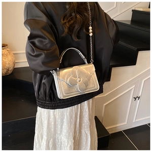 Detail of silver metallic handbag with 3D flower decoration and pearl chain strap