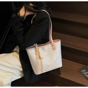Detail view of large white and pink floral tote bag worn by model on stairs