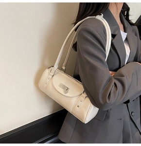 Détail d'un sac baguette crème minimaliste avec serrure coeur et rivets sur un tailleur
