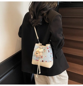 Fashionable woven bucket bag with cartoon patterns and plush bear charm on a model