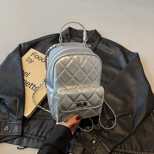 Close-up of silver quilted mini backpack featuring metallic texture and chain strap