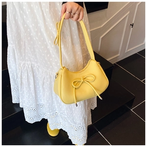 Detail of yellow lychee texture dumpling bag featuring chic leather bow and silver zipper