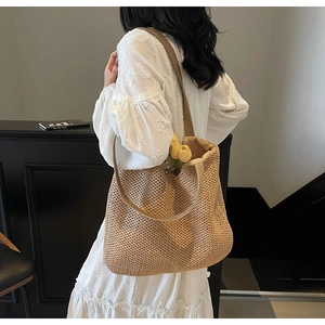Detail of handwoven straw hobo bag with natural wood brown texture and slim shoulder strap