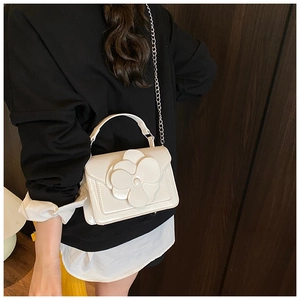 Detail view of the 3D flower decoration and silver metal chain strap on a white bag