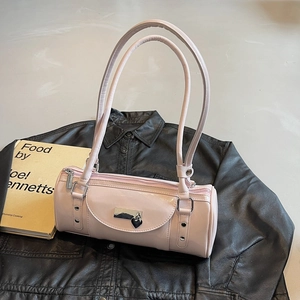 Détail d'un sac à épaule cylindrique rose avec breloque cœur argentée et rivets