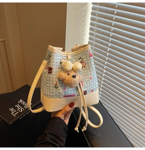 Detail view of sky blue tweed bucket bag with cartoon bear prints and plush charm