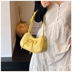 Detail of yellow bow shoulder bag showing lychee grain texture and minimalist aesthetic