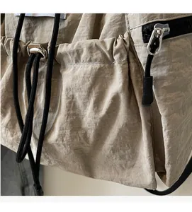 Macro detail of beige nylon backpack fabric featuring drawstring and metal fastener
