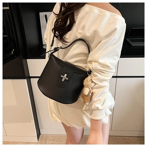 Detail of black lychee grain leather bucket bag with silver clasp and teddy bear charm