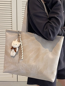 Minimalist large capacity tote bag with marble texture and bear charm worn by a model
