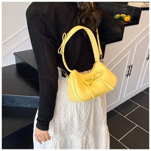 Rear view of a model wearing a bright yellow bow-knot hobo bag with litchi texture finish