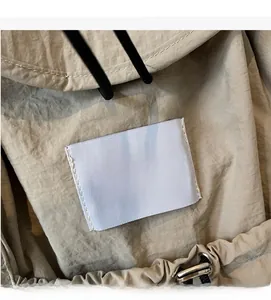 Close-up of beige nylon backpack fabric featuring a waswac rules woven label and drawstring