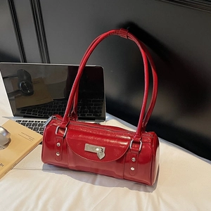 Détail du sac baguette en cuir verni rouge avec pendentif coeur et plaque en métal argenté