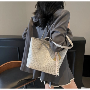 Detail of beige tote bag with geometric maze pattern and mini tennis racket charm