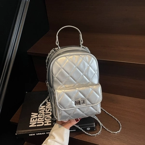 Detailed close-up of metallic silver quilted mini backpack with chain strap and metal lock