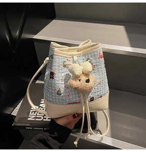 Detailed close-up of blue plaid bucket bag with sweet bear embroidery and plush charm