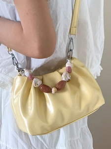 Pale yellow pleated cloud bucket bag with decorative marble beads and leather shoulder strap