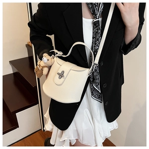 Detail of cream white litchi pattern bucket bag with silver clasp and bear charm