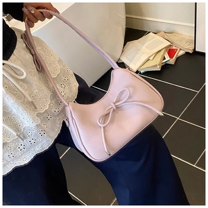 Detail view of pink dumpling bag featuring textured faux leather and a 3D bow accent