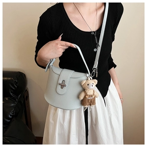 Detail view of mint green saddle bag featuring litchi texture and cute bear pendant