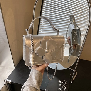 Detail view of silver flower bag with metallic chain and white pearl embellishments