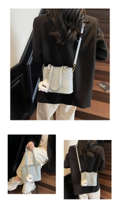 Detail of mint green leather bucket bag with plush charm and golden hardware accents