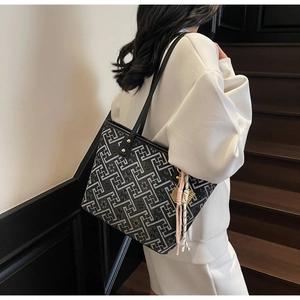 Detail view of large tote bag featuring geometric maze patterns and pink tassel charm